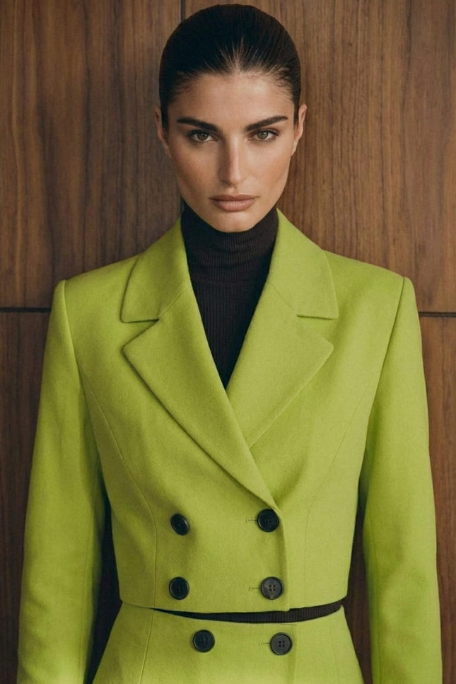 Woman wearing a bright green coat with black buttons against a wooden background