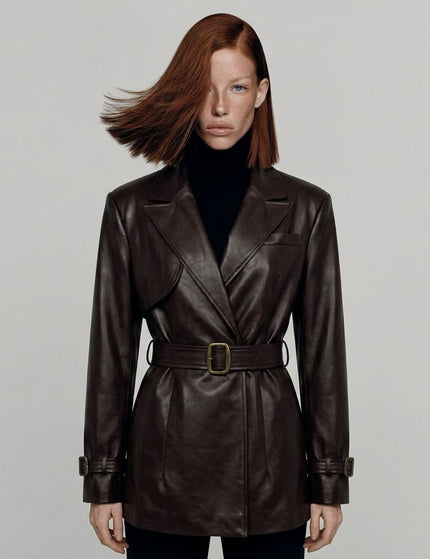 Woman wearing a brown leather coat with a belt on a plain background