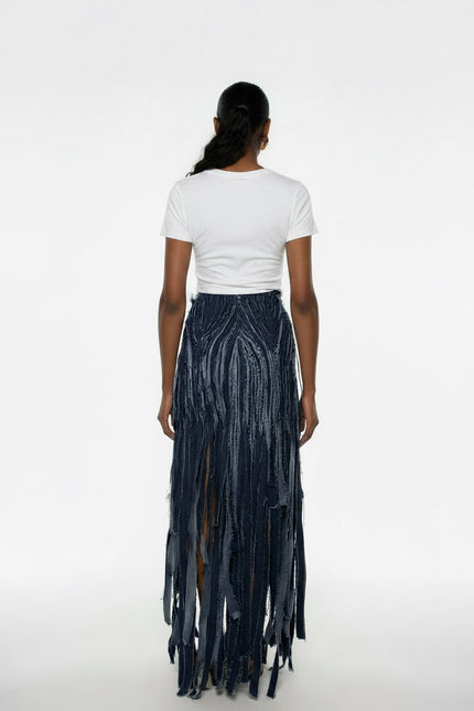 Person wearing a white t-shirt and dark fringe skirt on a white background