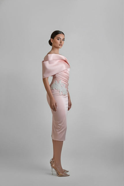 Woman wearing a light pink dress with a textured top on a gray background