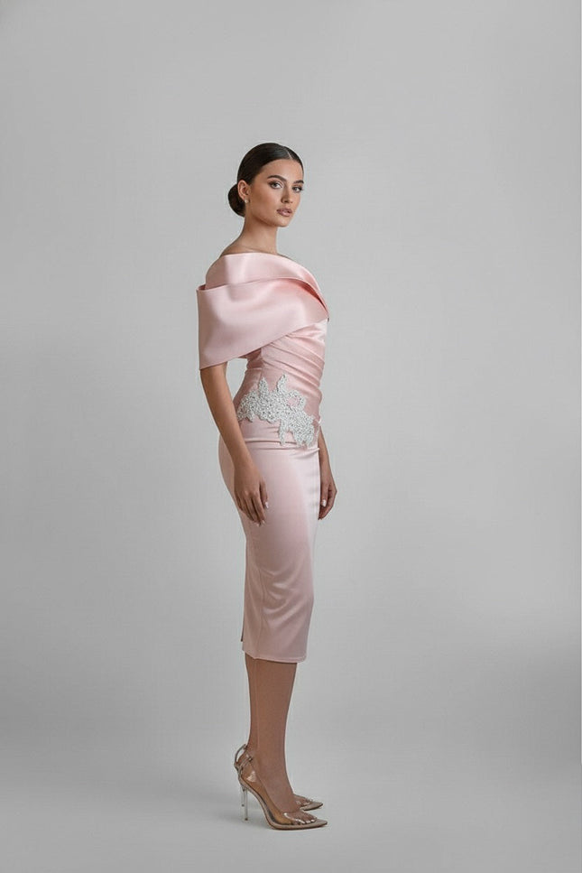Woman wearing a light pink dress with a textured top on a gray background