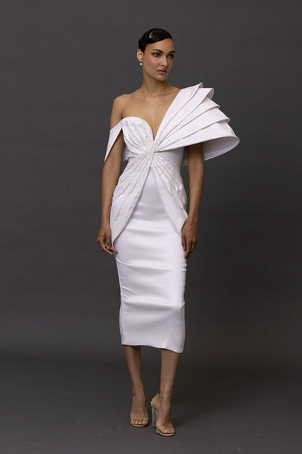 Woman wearing a white dress with a unique design on a dark background