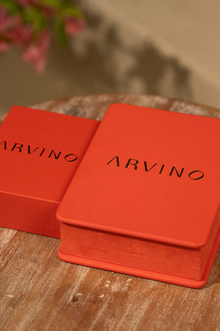 Two red ARVINO boxes on a wooden surface with a blurred floral background