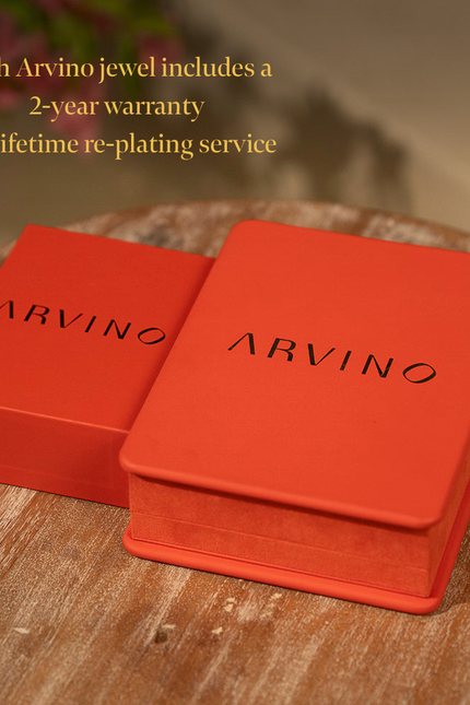 Two red Arvino jewelry boxes on a wooden surface with promotional text.
