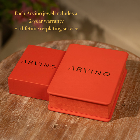 Two red Arvino jewelry boxes on a wooden surface with promotional text.