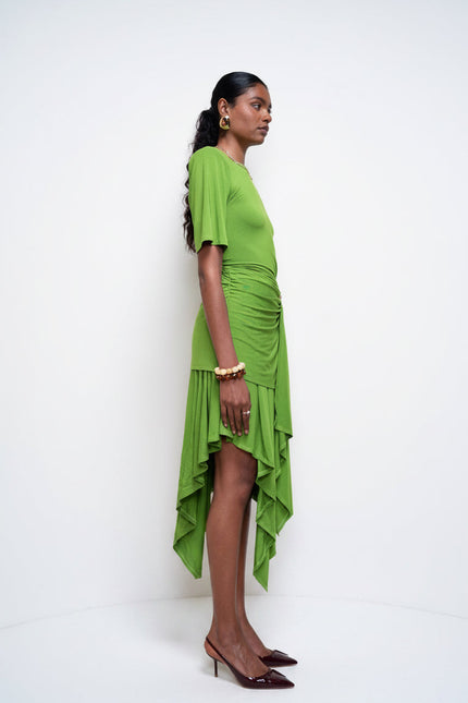 Woman wearing a green dress standing against a white wall