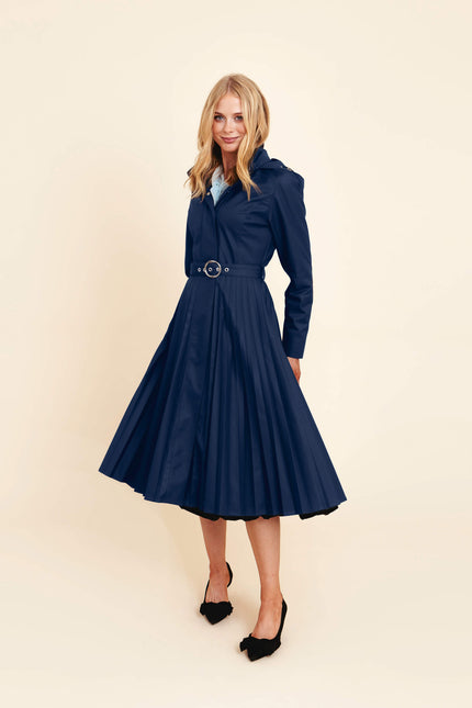 Woman wearing a blue coat named Blue Serenade with a belt on a beige background.