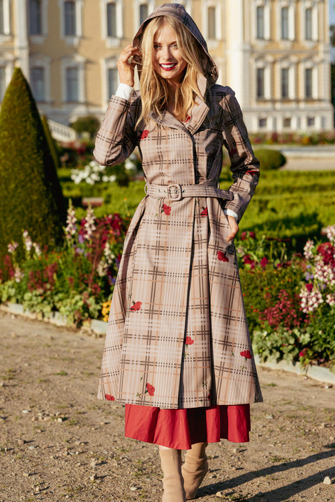 Woman in a plaid coat with red accents standing in a garden.