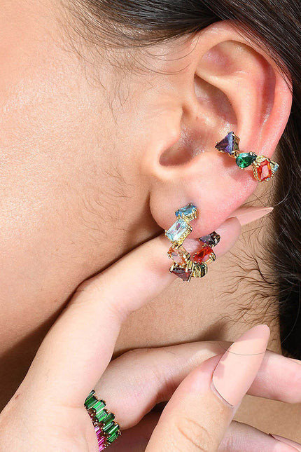A person wearing a colorful ear cuff with a sculptural design, featuring multiple droplet shapes adorned with rich hand-applied enamel.