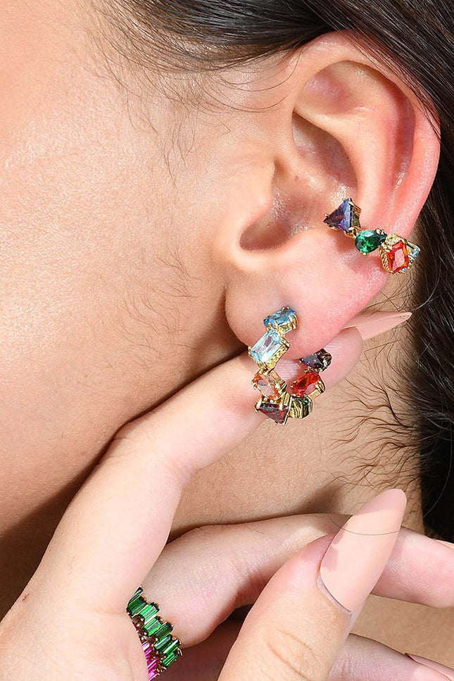 A person wearing a colorful ear cuff with a sculptural design, featuring multiple droplet shapes adorned with rich hand-applied enamel.