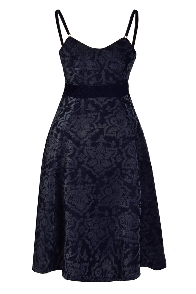 The Sarvin Jacquard Skater Dress is a sleeveless, knee-length black dress with velvet straps, fitted bodice, subtle floral jacquard pattern, A-line silhouette, and defined waistband for an elegant look.