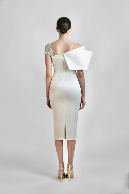 White evening gown with large bow detail on a plain background