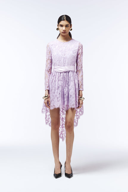 Back view of lilac lace occasion dress featuring sheer long sleeves and asymmetric hem.