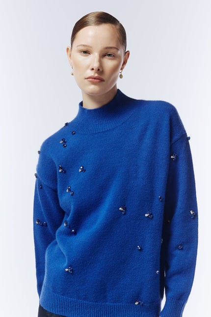 Close-up of hand-stitched gemstone detailing on the sapphire blue Sour Figs jumper.