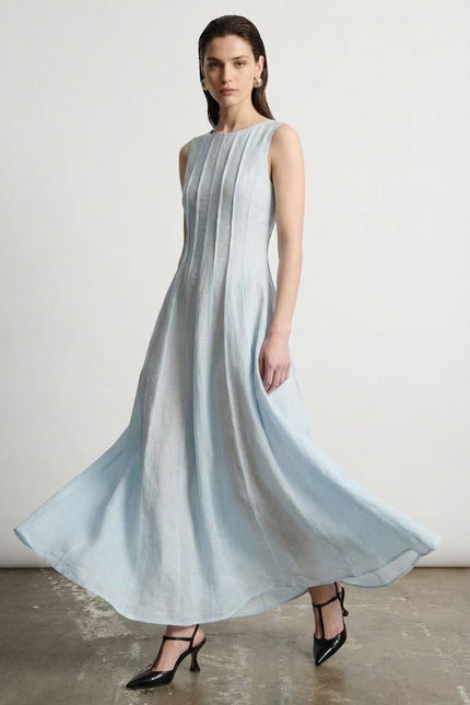 Woman wearing a light blue dress standing against a plain background