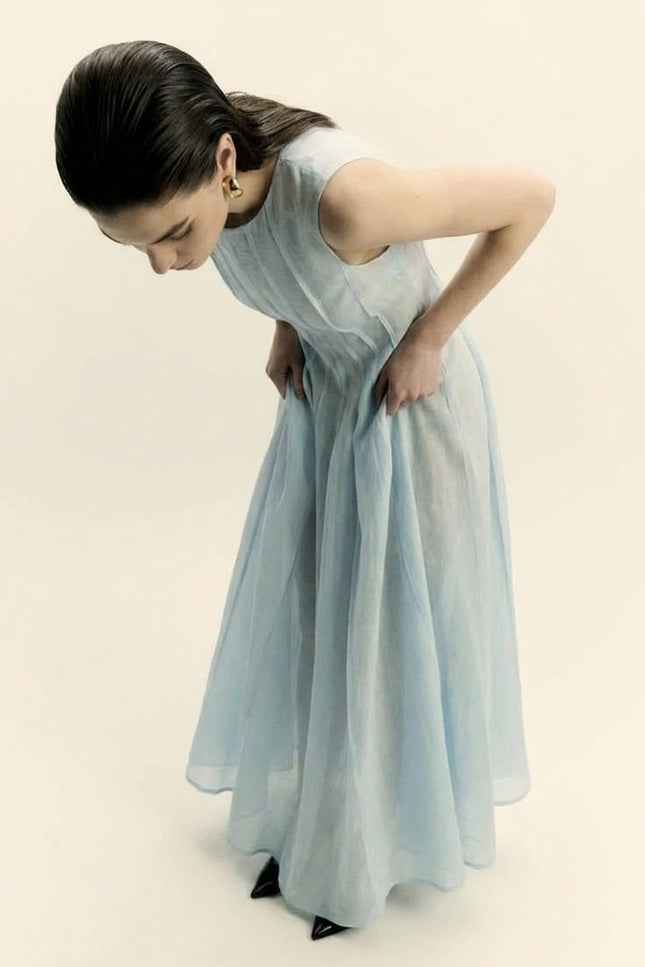Woman wearing a light blue dress against a beige background