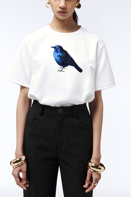 Close-up of the blue starling print on a white T-shirt tucked into black tailored trousers.