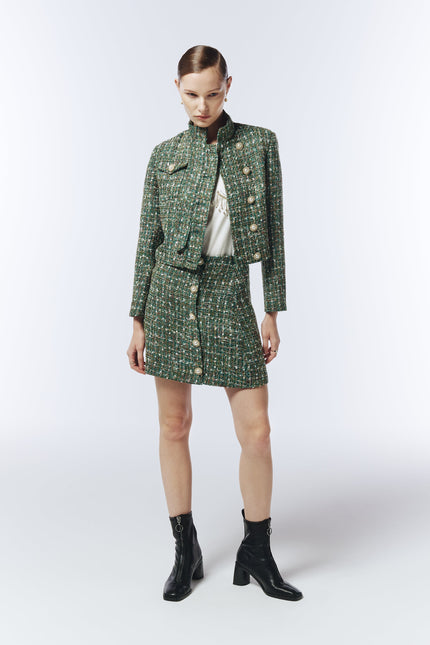Model wearing SOUR FIGS Cropped High-Neck Tweed Jacket in Emerald Green Mélange with matching mini skirt, showcasing luxury pearl buttons and structured silhouette — perfect for AW25 smart casual and evening looks.