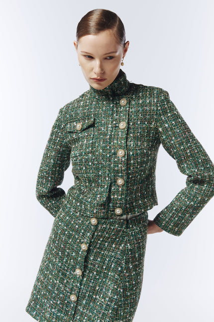 Editorial shot of SOUR FIGS Cropped High-Neck Tweed Jacket in Emerald Green Mélange styled with matching green check tweed skirt, capturing luxury modern tailoring and timeless sophistication.