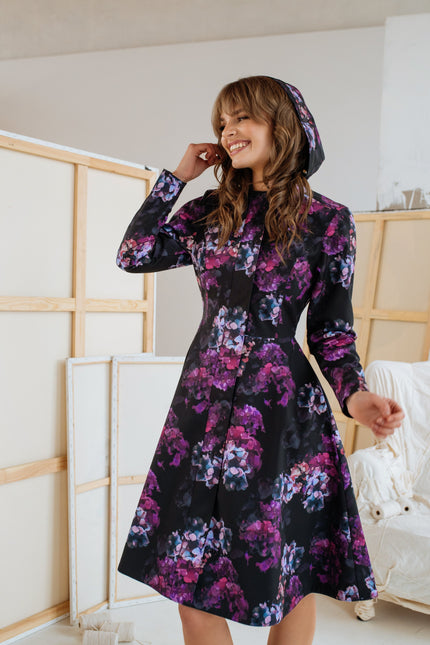Front view of the 'Hortense' coat – a purple and pink floral fit-and-flare design with a fitted top, A-line skirt, and adjustable hood, perfect for cooler weather.