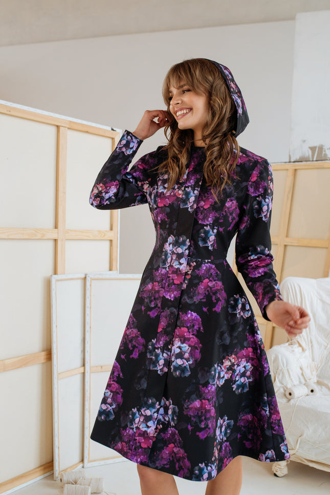 Front view of the 'Hortense' coat – a purple and pink floral fit-and-flare design with a fitted top, A-line skirt, and adjustable hood, perfect for cooler weather.