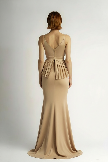 Woman wearing a beige peplum dress on a plain background