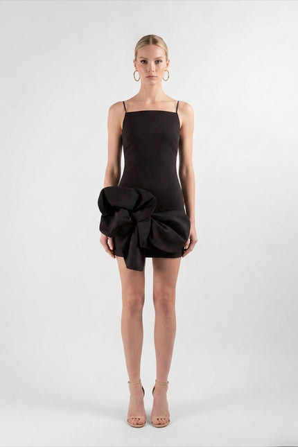 Woman wearing a black dress with a large bow detail on a white background