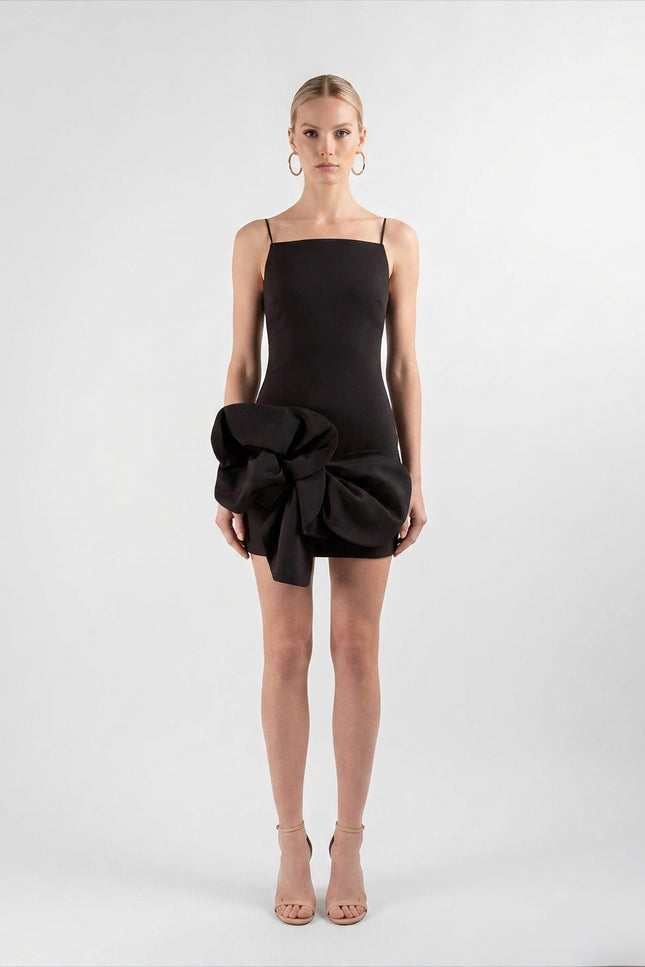 Woman wearing a black dress with a large bow detail on a white background