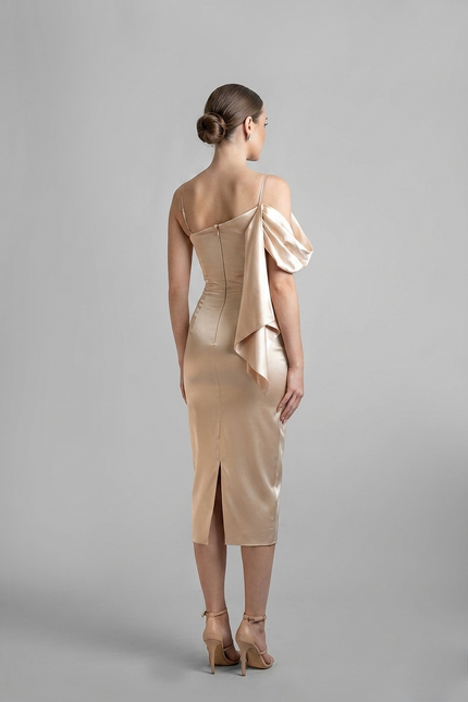 Woman wearing a beige dress with a draped detail on a gray background