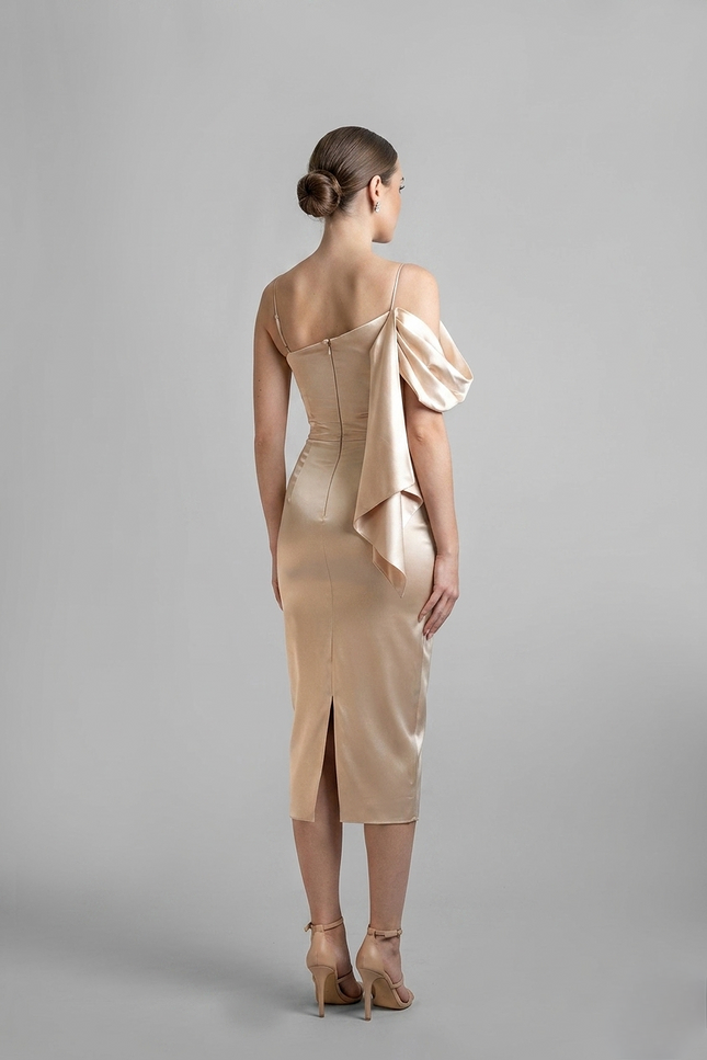 Woman wearing a beige dress with a draped detail on a gray background