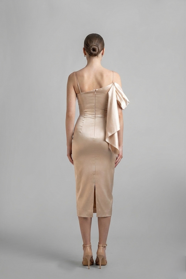 Woman wearing a beige dress with a draped detail on a gray background