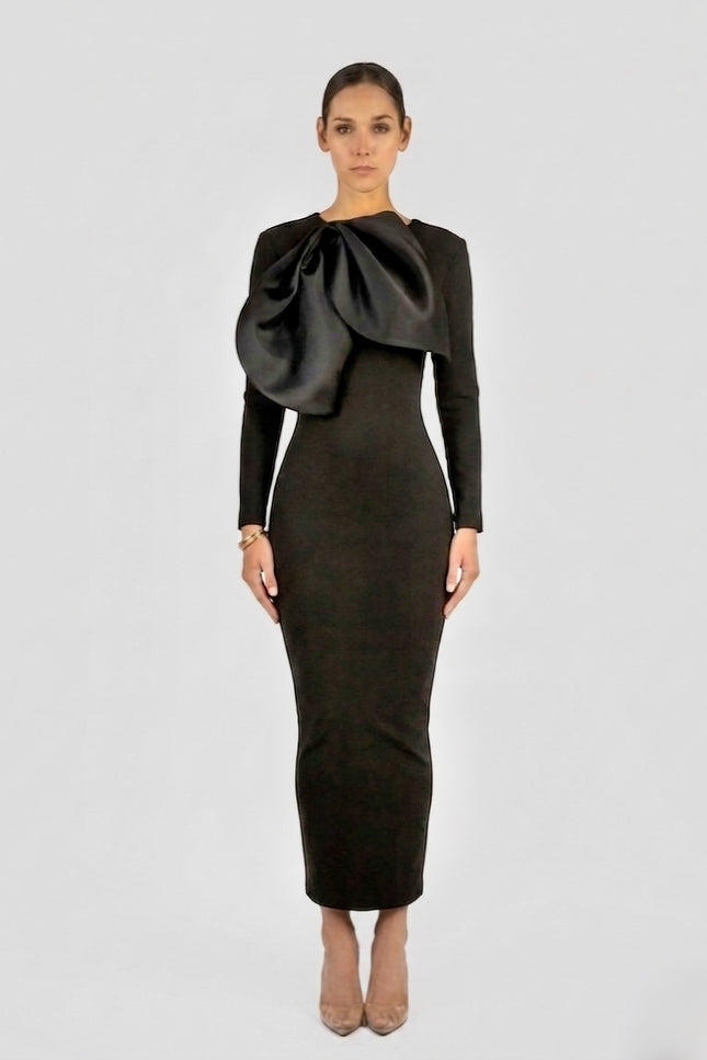 Black long-sleeve structured column maxi dress with oversized sculptural satin bow detail at chest, by Anitabel, styled with nude pointed heels