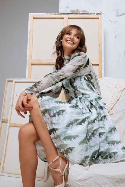 Model seated gracefully in the dress, with focus on the long sleeves and gathered shoulder details.