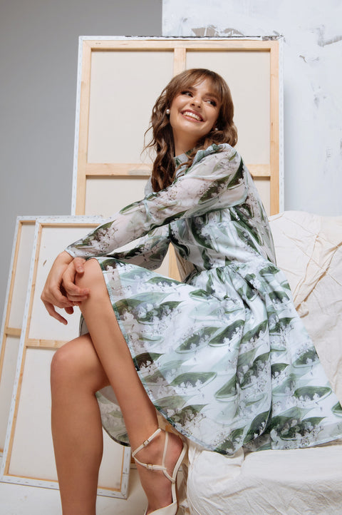 Model seated gracefully in the dress, with focus on the long sleeves and gathered shoulder details.