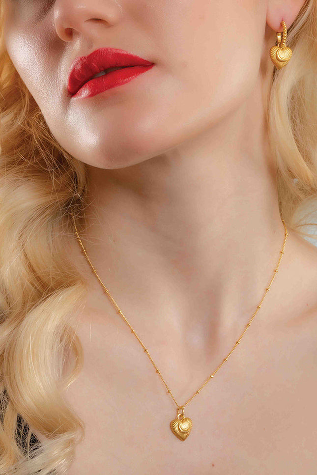 A woman wearing a gold-Plated pendant necklace with a heart-shaped pendant By Arvino