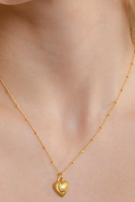 A gold-Plated pendant necklace with a crescent moon and heart design Pendant ,displayed on a person with long blonde hair.