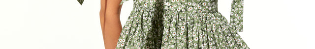 Woman wearing a green floral dress with tied straps on a white background