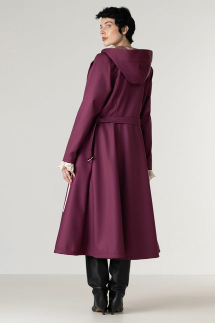 Full-length view of a women's berry double-breasted trench coat with a removable hood and elegant tailored silhouette.