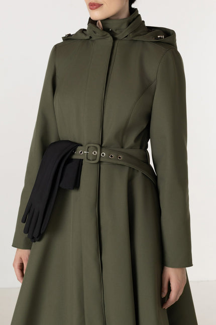 An moss green hooded coat with a matching waist belt and buckle, styled with black gloves, shown on a model against a plain light background.