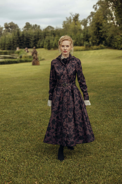 Outdoor full-length view of the Women's Brown Floral Fit and Flare Coat Brocade Dusk, a waterproof softshell coat with a feminine silhouette, flowing A-line skirt, and matching buckle belt.