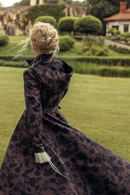 Editorial photo of the Women's Brown Floral Fit and Flare Coat Brocade Dusk highlighting the deep brown color, elegant black floral print, fitted bodice, and flowing A-line skirt.