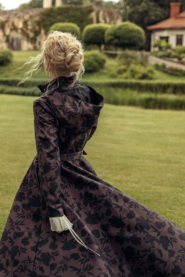 Editorial photo of the Women's Brown Floral Fit and Flare Coat Brocade Dusk highlighting the deep brown color, elegant black floral print, fitted bodice, and flowing A-line skirt.