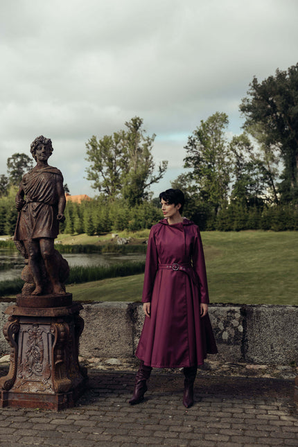 Women's berry double-breasted trench coat photographed outdoors, showcasing its elegant silhouette.