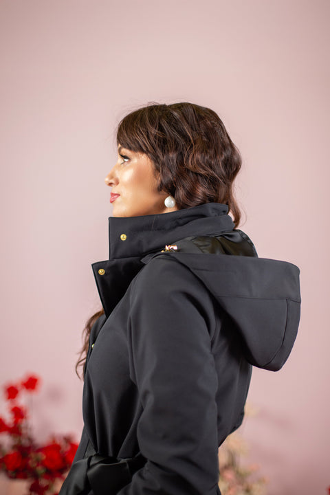 Side view of a stylish black coat with a bow-tie belt and adjustable hood.