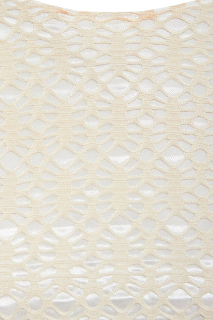 Close-up of Sarvin's Ivory Lace Backless Dress: cream-colored lace with a geometric hexagonal and oval pattern overlays a white background, showcasing the dress's textured detail.