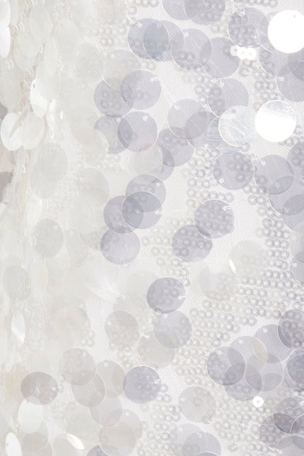 Close-up of shiny white sequins sewn onto sheer fabric, creating a textured, reflective look on the Sarvin White Sequin Backless Mini Dress—perfect for making a dazzling entrance.