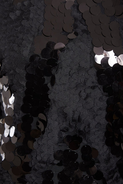 Close-up of the Sarvin Black Backless Sequin Mini Dress, featuring shiny round black sequins with an uneven texture from overlapping layers—reflecting light for a glamorous party-ready look.
