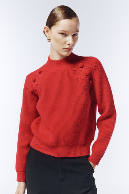 Close-up of integrated cable and bobble-knit detailing on shoulder of crimson jumper from SOUR FIGS
