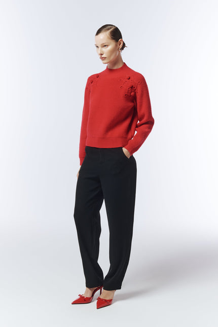 Side view of crimson bobble-knit jumper showing textured shoulder pattern.