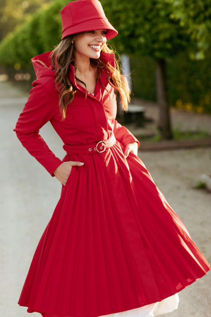 Woman wearing a red coat and hat outdoors.